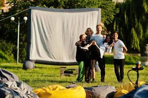 joven grupo multiétnico de personas viendo películas en poof en cine al aire libre. foto