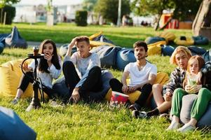 Young multi ethnic group of people watching movie at poof in open air cinema. photo