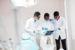 Three african american male doctors working, discussing with colleagues in clinic. photo