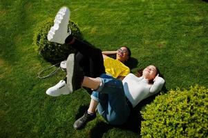 White caucasian girl and black African American together lying on grass. World unity, racial love, understanding in tolerance and races diversity cooperation. photo