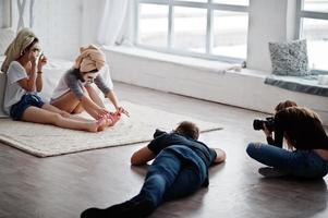 el equipo de dos fotógrafos fotografiando a las gemelas del estudio mientras hacen su propia crema para máscaras. fotógrafo profesional en el trabajo. foto