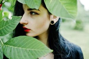 Sensual girl all in black, red lips and earlobe piersing. Goth dramatic woman. photo