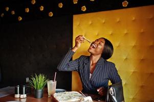 mujer de negocios afroamericana comiendo pizza de queso en la cafetería. chica negra descansando. foto