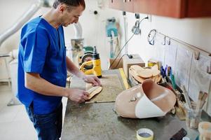 Prosthetist man making orthopedic insoles while working in laboratory. photo