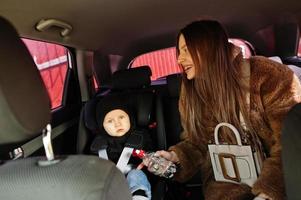 Young mother and child in car. Baby seat on chair. Safety driving concept. photo