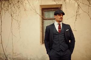 Portrait of retro 1920s english arabian business man wearing dark suit, tie and flat cap. photo