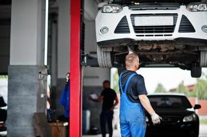 Car repair and maintenance theme. Mechanic in uniform working in auto service. photo