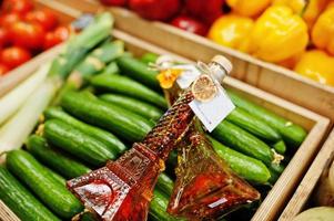 dos frascos de aceite de oliva virgen con condimentos en botella como la torre eifel en el estante con pepinos en el supermercado o tienda de comestibles. hecho con amor. foto