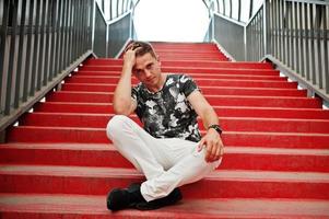 retrato de estilo de vida de un hombre guapo posando en las escaleras rojas del tonnel de la ciudad. foto