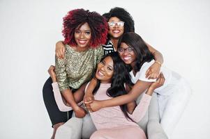 Happy brightful positive moments of four african girls. Having fun and smiling on chair against white empty wall. Lovely moments of four hugging best friends. photo