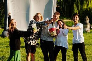 Young multi ethnic group of people watching movie at poof in open air cinema. photo