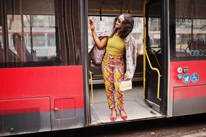 Young stylish african american woman in modern sunglasses riding on a bus. photo
