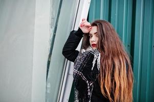 Brunette stylish casual girl in scarf against green metallic wall. photo