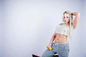 Blonde sporty girl with yellow dumbbell posed at studio against white background. photo