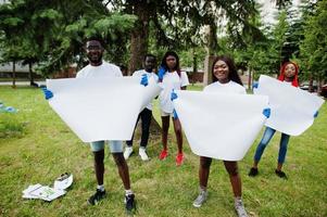 Group of happy african volunteers hold empty blank board in park. Africa volunteering, charity, people and ecology concept. Free space for your text. photo