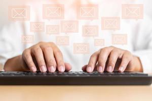 mano de mujer escribiendo en el concepto de teclado de recibir o enviar icono de correo electrónico en el escritorio de trabajo con computadora portátil foto