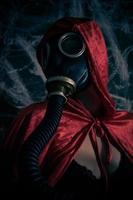 Woman in red gown wearing an old gas mask photo