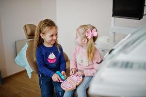 Two cutie little baby girls at dentist chair. Children dental. photo