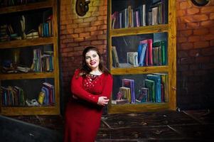 Brunette plus size model against wall like library. photo