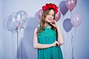 Happy girl in green turqoise dress and wreath with colored balloons isolated on white. Celebrating birthday theme. photo