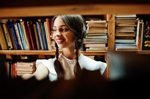 Girl with pigtails in white blouse at old library. photo