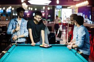 Group of stylish asian friends wear on jeans playing pool billiard on bar. photo