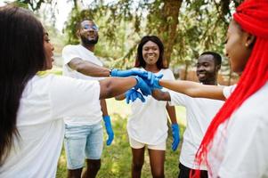 un grupo de felices voluntarios africanos puso las manos en las manos en el parque. Concepto de voluntariado, caridad, personas y ecología de África. foto