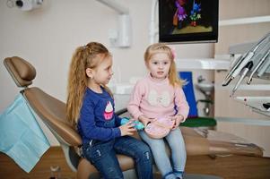 Two cutie little baby girls at dentist chair. Children dental. photo