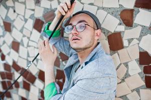 hombre macho con estilo soñador en traje gris, sombrero y gafas posadas en el techo. foto