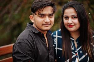 historia de amor de una pareja india posada al aire libre, sentada en un banco juntos. foto