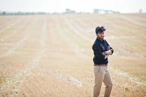 South asian agronomist farmer inspecting wheat field farm. Agriculture production concept. photo