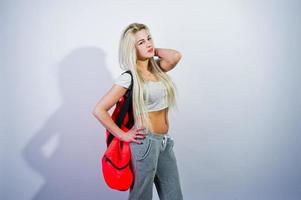 Chica rubia deportiva con una gran bolsa deportiva posada en el estudio con fondo blanco. foto