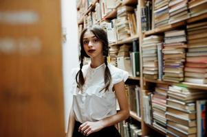 Girl with pigtails in white blouse at old library. photo