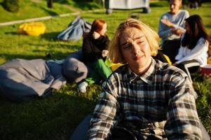 Young multi ethnic group of people watching movie at poof in open air cinema. Close up portrait of funny guy. photo