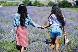 Two beautiful indian girls in purple lavender field. photo