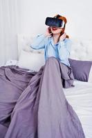 Red haired girl in bed with vr glasses at studio room. photo