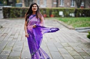 Indian hindu girl at traditional violet saree posed at autumn street. photo