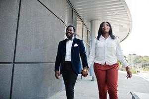 Stylish african american couple in formal wear walking with holding hands together. Romantic couple in love dating. photo