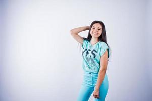 Portrait of a young beautiful woman in blue or turquoise t-shirt and trousers posing in the studio. photo