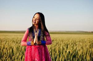 Tender indian girl in saree, with violet lips make up posed at field in sunset. Fashionable india model. photo