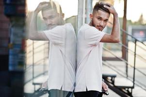 hombre de barba india con estilo en camiseta rosa. modelo india posó al aire libre en las calles de la ciudad contra el espejo de la ventana. foto