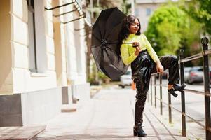 Portrait of young beautiful african american woman holding black umbrella. photo