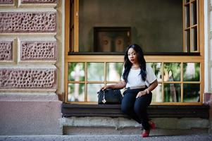 Stylish african american business woman with handbag on streets of city. photo