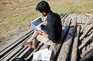 South asian agronomist farmer looking at diagram papers on farm. Agriculture production concept. photo