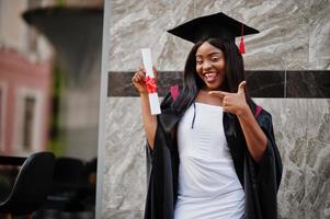 joven estudiante afroamericana con diploma posa al aire libre. foto