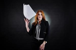 Portrait of a redheaded businesswoman in striped blouse and jacket throwing the paper away. photo