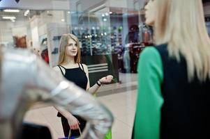 chica con bolsas de compras en el centro comercial mirando maniquíes en el escaparate. foto