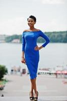 chica rizada afroamericana posó en la calle de la ciudad con vestido azul. foto