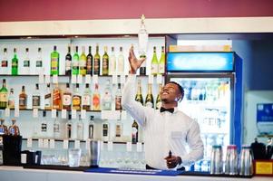 African american bartender at bar flair in action, working behind the cocktail bar. Alcoholic beverage preparation. photo