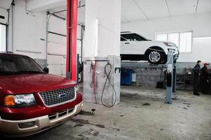 Two american SUV car on stand for wheels alignment camber check in workshop of service station. photo